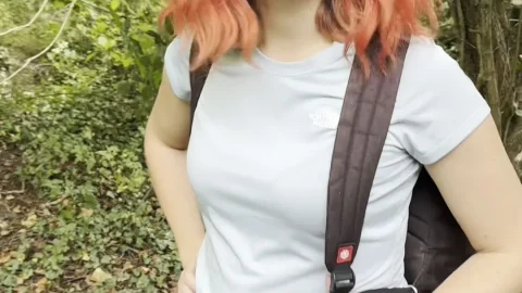 Redheaded girl with leg tattoos walks and poses in forest with backpac