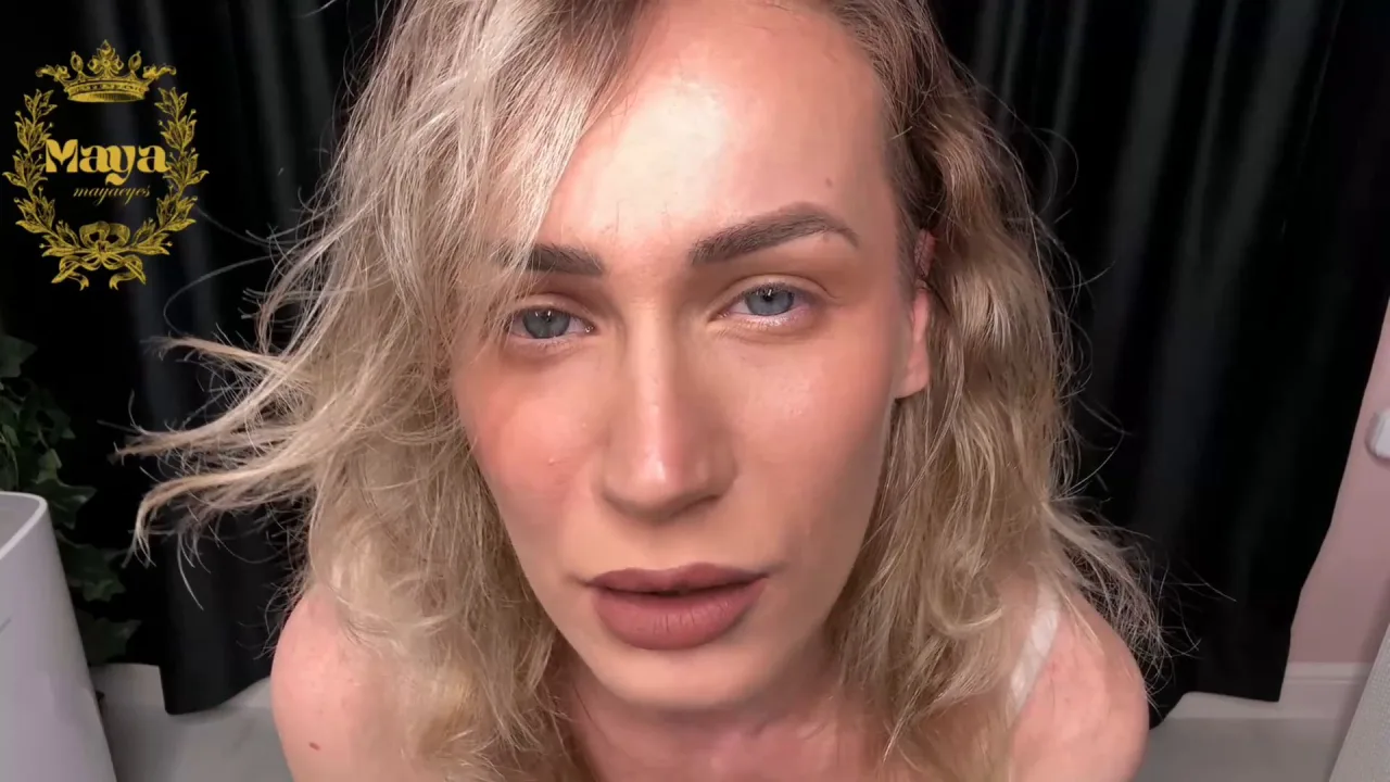 Blonde in black talks to camera with softbox lighting near plant